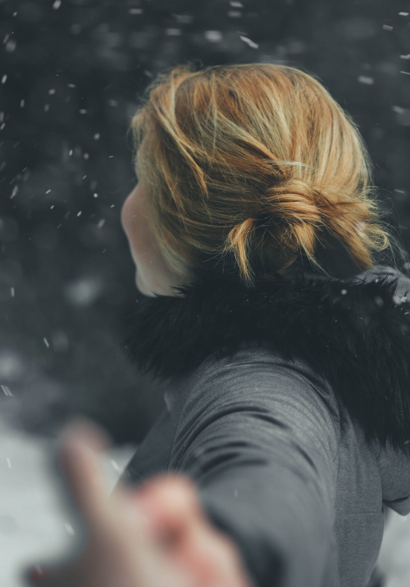 Frau von hinten mit hochgesteckten Haaren, tanzt im Schnee