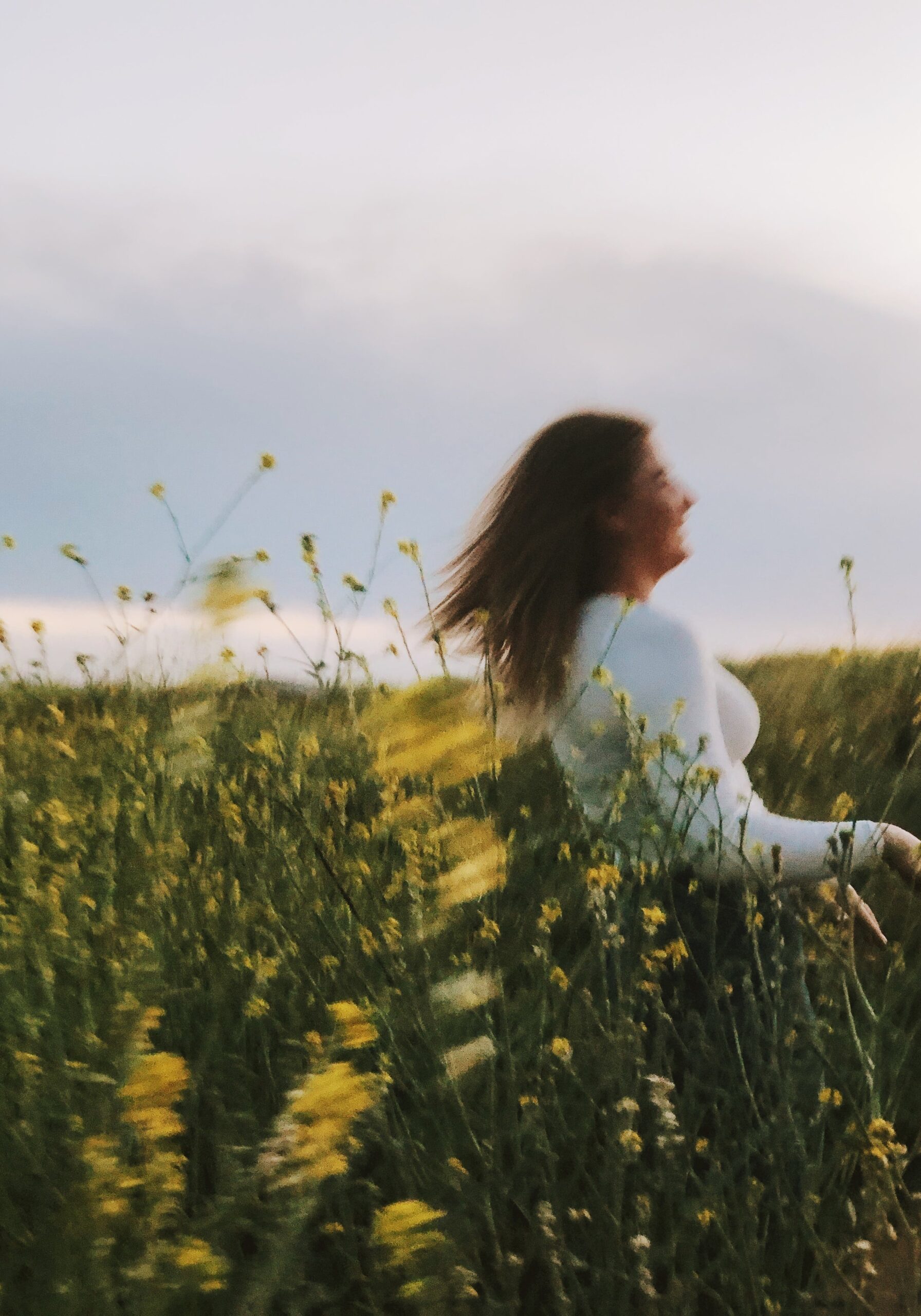 Frau, unscharf abgebildet, rennt lachend durch eine Blumenwiese